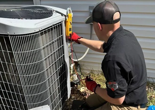Technician checking an outdoor condenser beside a home