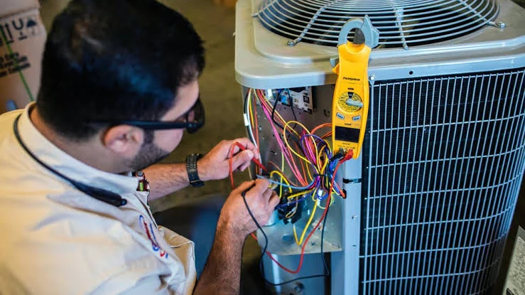 Technician using a clamp meter to test air conditioning wiring