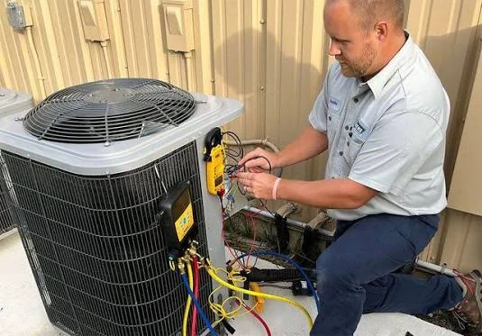 Technician taking electrical readings at an outdoor HVAC unit