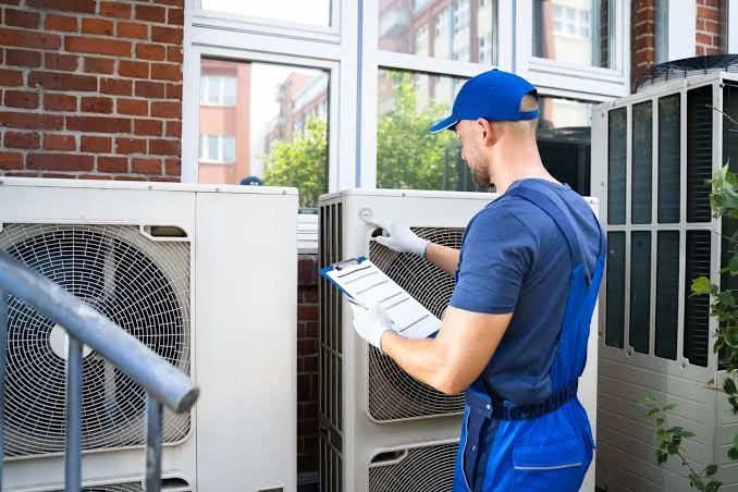 Technician with a clipboard inspecting outdoor heating and cooling equipment